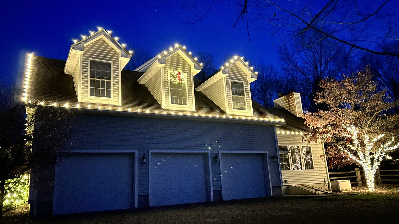 Permanent LED roofline lighting on an upscale home at dusk